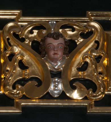 Zdjęcie nr 36: Ołtarz architektoniczny, na wysokim cokole, jednokondygnacyjny, trójosiowy, ze zwieńczeniem; osie wyznaczone umieszczonymi na wysokich cokołach kolumnami o kapitelach kompozytowych, podtrzymującymi występujące nad podporami uproszczone belkowanie i gzyms, ponad nimi trójkątny, przerywany przyczółek. W strefie dolnej, w osiach skrajnych, po bokach mensy bramki zamknięte półkoliście, służące do obejścia ołtarza. Mensa prostopadłościenna, o profilowanym obramieniu antependium i z profilowanymi prostokątnymi płycinami na bokach. Powyżej, w pierwszej kondygnacji, w osiach skrajnych nisze zamknięte łukiem półkolistym z konchami muszlowymi, w osi środkowej prostokątna wnęka na obraz ołtarzowy. Płyciny na cokołach, powyżej półkolistych wnęk oraz na predelli ażurowe, w kształcie prostokąta z uszakami. Zwieńczenie jednoosiowe, flankowane kolumienkami o kapitelach kompozytowych, z występującym nad podporami belkowaniem i gzymsem oraz półkolistym przerywanym przyczółkiem. W polu środkowym owalna profilowana nisza na obraz, ponad którą w szczycie ołtarza gloria promienista. Nastawa flankowana uszakami w z motywów ornamentu małżowinowo-chrząstkowego. Belkowanie, profilowane, prostokątne pole na obraz, predella oraz płyciny na cokołach i powyżej półkolistych wnęk, wypełnione ornamentem małżowinowo-chrząstkowym. Powyżej bramek w części cokołowej podwieszone girlandy. W zwieńczeniu małżowinowo-chrząstkowe uszaki oraz płyciny wypełnione ornamentem małżowinowo-chrząstkowym. W narożach stylizowane liście. Profilowana wnęka na obraz w zwieńczeniu  wypełniona lilijkami. Kolumny, gzymsy i profilowania otworów złocone. Gloria promienista z puttami oraz Okiem Opatrzności na tle trójkąta równobocznego. Antepedium ozdobione romboidalną siatką, w narożach wstęga regencyjna przechodząca w akant. Pośrodku litery IHS w glorii promienistej. W płycinach na cokołach i powyżej wnęk główki puttów. W niszach rzeźby św. Wojciecha i św. Stanisława. W centralnym polu obraz z przedstawieniem św. Grzegorza Wielkiego, w zwieńczeniu Wniebowzięcie Najświętszej Marii Panny. Na przerywanym przyczółku nastawy rzeźby aniołów. Rzeźba anioła po lewej stronie, pełna, całopostaciowa. Anioł ukazany w pozycji półleżącej, w trzech czwartych, z lewą nogą wysuniętą i wzniesioną głową. Ręce ugięte w łokciach i uniesione. Twarz pociągła, włosy ciemne, kręcone, sięgające do ramion i odsłaniające uszy. Anioł odziany jest w długą, złotą suknię, z podwiniętymi rękawami i odsłaniającą lewą nogę. Fałdy głęboko rzeźbione, na kształt litery V i pionowych rurek.Rzeźba anioła po prawej, pełna, całopostaciowa. Anioł ukazany w pozycji półleżącej, w trzech czwartych, z lewą nogą wysuniętą i wzniesioną głową. Lewa ręka ugięta w łokciu i ułożona na piersi, prawa wyprostowana. Twarz pociągła, włosy ciemne, kręcone, sięgające do ramion i odsłaniające uszy. Anioł ubrany w długą, złotą suknię, z podwiniętymi rękawami i odsłaniającą lewą nogę. Fałdy głęboko rzeźbione, na kształt litery V i pionowych rurek.