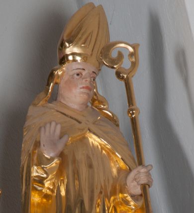 Zdjęcie nr 1: Rzeźba polichromowana i złocona. Święty ukazany frontalnie, w pozycji stojącej, z prawą ręką ugiętą w łokciu i z otwartą dłonią uniesioną na wysokości piersi, skierowaną do widza w wymownym geście. W lewej trzyma pastorał. U jego stóp, z prawej strony przedstawiono z profilu, w pozycji klęczącej Piotrowina, ze złożonymi rękoma, z twarzą uniesioną ku górze, skierowaną w stronę Świętego. Stanisław ubrany w strój liturgiczny: albę, rokietę i kapę spiętą na piersiach. Szaty złote, pofałdowane. Suknia Piotrowina w kolorze niebieskim. Karnacje w kolorze naturalnym.