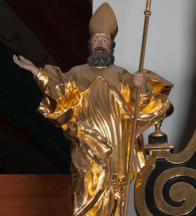 Zdjęcie nr 2: Rzeźba ścięta z tyłu, polichromowana. Święty Wojciech ukazany frontalnie, stojący w lekkim kontrapoście, ciężar ciała wspierający na lewej nodze; prawą rękę, odstawioną od boku, unosi na wysokość piersi, lewą wspiera na pastorale. Twarz okolona gęstą, długą brodą z wąsami. Święty ubrany w długie, złote, mocno fałdowane szaty. Na głowie mitra biskupia. Karnacje w kolorze naturalnym.