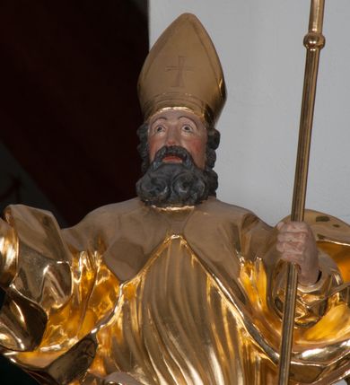 Zdjęcie nr 3: Rzeźba ścięta z tyłu, polichromowana. Święty Wojciech ukazany frontalnie, stojący w lekkim kontrapoście, ciężar ciała wspierający na lewej nodze; prawą rękę, odstawioną od boku, unosi na wysokość piersi, lewą wspiera na pastorale. Twarz okolona gęstą, długą brodą z wąsami. Święty ubrany w długie, złote, mocno fałdowane szaty. Na głowie mitra biskupia. Karnacje w kolorze naturalnym.