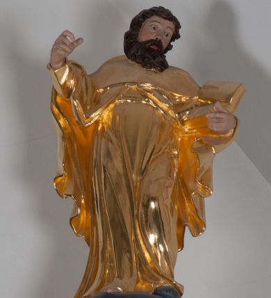 Zdjęcie nr 1: Rzeźba ścięta z tyłu, polichromowana, złocona. Święty Jakub Starszy ukazany frontalnie, w lekkim kontrapoście, ciężar ciała wspierający na prawej nodze, w lewej ręce trzyma księgę, prawą unosi na wysokość piersi. Twarz okolona czarnymi, krótkimi, kędzierzawymi włosami i zarostem. Święty ubrany w złote szaty. Tunika długa, układająca się w miękkie płytkie fałdy, płaszcz długi, spięty na piersi, okrywa ramiona i plecy. Na plecach kapelusz.