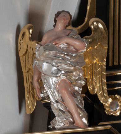 Zdjęcie nr 1: Anioł nad lewą kolumną ujęty w kontrapoście, z lewą ręką przyłożoną do torsu. Głowa odchylona na lewe ramię. Skrzydła złocone, umieszczone symetrycznie. Malowane w kolorze naturalnym, nagie ciało okryte srebrną, fałdowaną draperią. Prawe ramię i lewa noga poniżej uda odsłonięta. Anioł nad prawą kolumną ujęty w ruchu, z lewą nogą wysuniętą do przodu i prawą do tyłu. Prawa ręka przyciśnięta do piersi, Głowa lekko pochylona w prawo. Skrzydła złocone, umieszczone symetrycznie. Nagie ciało, pomalowane w tonacji naturalnej, okryte srebrną, fałdowaną szatą. Ramiona i lewa noga poniżej uda odsłonięte. Anioł na zwieńczeniu stoi na spadzistym cokole, z kolanami lekko ugiętymi, pochylony. Obiema rękami trzyma srebrny księżyc o cechach antropomorficznych. Głowa anioła lekko pochylona w prawo. Nagie, malowane w tonacji naturalnej ciało okryte srebrnym, fałdowanym płaszczem. Odkryte prawe ramię i ręka oraz widoczne stopy. Skrzydła złocone, umieszczone symetrycznie.