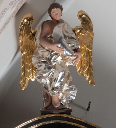 Zdjęcie nr 4: Anioł nad lewą kolumną ujęty w kontrapoście, z lewą ręką przyłożoną do torsu. Głowa odchylona na lewe ramię. Skrzydła złocone, umieszczone symetrycznie. Malowane w kolorze naturalnym, nagie ciało okryte srebrną, fałdowaną draperią. Prawe ramię i lewa noga poniżej uda odsłonięta. Anioł nad prawą kolumną ujęty w ruchu, z lewą nogą wysuniętą do przodu i prawą do tyłu. Prawa ręka przyciśnięta do piersi, Głowa lekko pochylona w prawo. Skrzydła złocone, umieszczone symetrycznie. Nagie ciało, pomalowane w tonacji naturalnej, okryte srebrną, fałdowaną szatą. Ramiona i lewa noga poniżej uda odsłonięte. Anioł na zwieńczeniu stoi na spadzistym cokole, z kolanami lekko ugiętymi, pochylony. Obiema rękami trzyma srebrny księżyc o cechach antropomorficznych. Głowa anioła lekko pochylona w prawo. Nagie, malowane w tonacji naturalnej ciało okryte srebrnym, fałdowanym płaszczem. Odkryte prawe ramię i ręka oraz widoczne stopy. Skrzydła złocone, umieszczone symetrycznie.