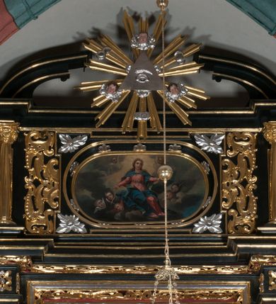 Zdjęcie nr 4: Obraz o kształcie leżącego owalu. Obraz przedstawia scenę Wniebowzięcia Najświętszej Marii Panny. Matka Boska ukazana jako siedząca na obłokach, z rozłożonymi na boki rękoma, w asyście anielskich putt, na tle obłoków i rozświetlonego  pośrodku nieba. Odziana jest w czerwoną suknię z długimi rękawami, przewiązaną w pasie, oraz niebieski płaszcz, zarzucony na ramiona i spięty na piersiach. Twarz owalna, z wydatnym nosem, okolona długimi jasnym włosami spływającymi na ramiona i plecy.  Wokół głowy gloria promienista.
