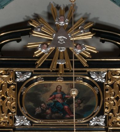 Zdjęcie nr 2: Obraz o kształcie leżącego owalu. Obraz przedstawia scenę Wniebowzięcia Najświętszej Marii Panny. Matka Boska ukazana jako siedząca na obłokach, z rozłożonymi na boki rękoma, w asyście anielskich putt, na tle obłoków i rozświetlonego  pośrodku nieba. Odziana jest w czerwoną suknię z długimi rękawami, przewiązaną w pasie, oraz niebieski płaszcz, zarzucony na ramiona i spięty na piersiach. Twarz owalna, z wydatnym nosem, okolona długimi jasnym włosami spływającymi na ramiona i plecy.  Wokół głowy gloria promienista.
