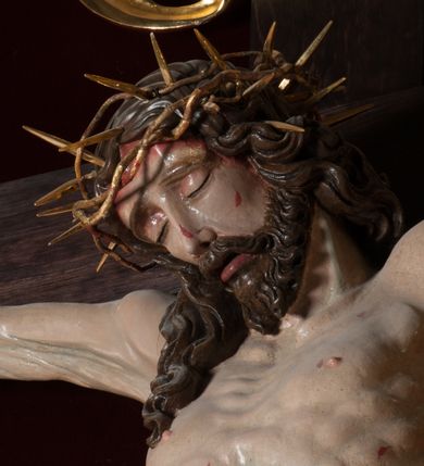 Zdjęcie nr 4: Chrystus, w typie Christo morto, rozpięty na drewnianym, prostym krzyżu łacińskim z titulusem z napisem INRI ujętym małżowiną. Chrystus przybity trzema gwoździami, w lekkim zwisie ciała i nogami ugiętymi w kolanach, ze stopami założonymi prawa na lewą. Na biodrach złocone, pofałdowane perizonium przytrzymywany sznurem; prawe biodro odsłonięte. Ciało smukłe, szczupłe, z wyraźnie zaznaczoną muskulaturą, ścięgnami i żebrami. Karnacja jasna ze strużkami krwi wypływającymi z ran. Głowa w koronie cierniowej, opuszczona i przechylona na prawy bark. Oczy zamknięte. Włosy brązowe, długie, kręcone, broda o rozdwojonych końcach. Na głowie korona cierniowa.