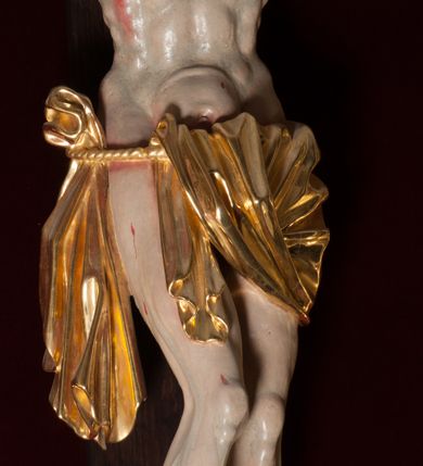 Zdjęcie nr 8: Chrystus, w typie Christo morto, rozpięty na drewnianym, prostym krzyżu łacińskim z titulusem z napisem INRI ujętym małżowiną. Chrystus przybity trzema gwoździami, w lekkim zwisie ciała i nogami ugiętymi w kolanach, ze stopami założonymi prawa na lewą. Na biodrach złocone, pofałdowane perizonium przytrzymywany sznurem; prawe biodro odsłonięte. Ciało smukłe, szczupłe, z wyraźnie zaznaczoną muskulaturą, ścięgnami i żebrami. Karnacja jasna ze strużkami krwi wypływającymi z ran. Głowa w koronie cierniowej, opuszczona i przechylona na prawy bark. Oczy zamknięte. Włosy brązowe, długie, kręcone, broda o rozdwojonych końcach. Na głowie korona cierniowa.