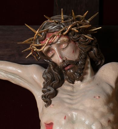 Zdjęcie nr 7: Chrystus, w typie Christo morto, rozpięty na drewnianym, prostym krzyżu łacińskim z titulusem z napisem INRI ujętym małżowiną. Chrystus przybity trzema gwoździami, w lekkim zwisie ciała i nogami ugiętymi w kolanach, ze stopami założonymi prawa na lewą. Na biodrach złocone, pofałdowane perizonium przytrzymywany sznurem; prawe biodro odsłonięte. Ciało smukłe, szczupłe, z wyraźnie zaznaczoną muskulaturą, ścięgnami i żebrami. Karnacja jasna ze strużkami krwi wypływającymi z ran. Głowa w koronie cierniowej, opuszczona i przechylona na prawy bark. Oczy zamknięte. Włosy brązowe, długie, kręcone, broda o rozdwojonych końcach. Na głowie korona cierniowa.