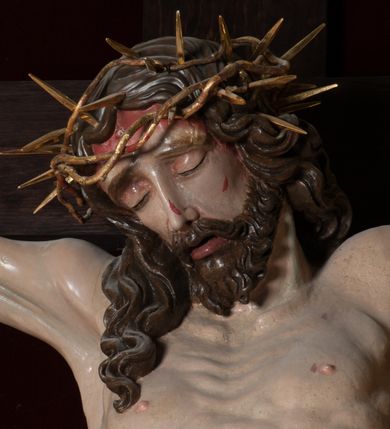 Zdjęcie nr 6: Chrystus, w typie Christo morto, rozpięty na drewnianym, prostym krzyżu łacińskim z titulusem z napisem INRI ujętym małżowiną. Chrystus przybity trzema gwoździami, w lekkim zwisie ciała i nogami ugiętymi w kolanach, ze stopami założonymi prawa na lewą. Na biodrach złocone, pofałdowane perizonium przytrzymywany sznurem; prawe biodro odsłonięte. Ciało smukłe, szczupłe, z wyraźnie zaznaczoną muskulaturą, ścięgnami i żebrami. Karnacja jasna ze strużkami krwi wypływającymi z ran. Głowa w koronie cierniowej, opuszczona i przechylona na prawy bark. Oczy zamknięte. Włosy brązowe, długie, kręcone, broda o rozdwojonych końcach. Na głowie korona cierniowa.