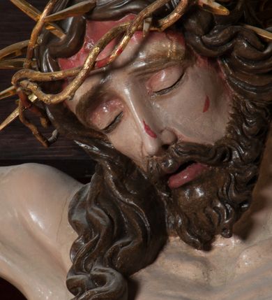Zdjęcie nr 5: Chrystus, w typie Christo morto, rozpięty na drewnianym, prostym krzyżu łacińskim z titulusem z napisem INRI ujętym małżowiną. Chrystus przybity trzema gwoździami, w lekkim zwisie ciała i nogami ugiętymi w kolanach, ze stopami założonymi prawa na lewą. Na biodrach złocone, pofałdowane perizonium przytrzymywany sznurem; prawe biodro odsłonięte. Ciało smukłe, szczupłe, z wyraźnie zaznaczoną muskulaturą, ścięgnami i żebrami. Karnacja jasna ze strużkami krwi wypływającymi z ran. Głowa w koronie cierniowej, opuszczona i przechylona na prawy bark. Oczy zamknięte. Włosy brązowe, długie, kręcone, broda o rozdwojonych końcach. Na głowie korona cierniowa.