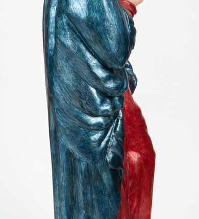 Zdjęcie nr 3: Rzeźba pełnoplastyczna, ukazująca Matkę Boską Bolesną w całej postaci. Matka Boska stoi w lekkim kontrapoście, ciężar ciała wspierając na prawej nodze, z dłońmi splecionymi na wysokości piersi w modlitewnym geście, z głową lekko odchyloną do tyłu i wzrokiem skierowanym ku górze. Twarz potraktowana schematycznie. Maria ubrana w czerwoną suknię przepasaną brązowym sznurem i niebieski płaszcz założony na głowę i barki, podtrzymywany z przodu przedramionami. Wokół szyi biała chusta.