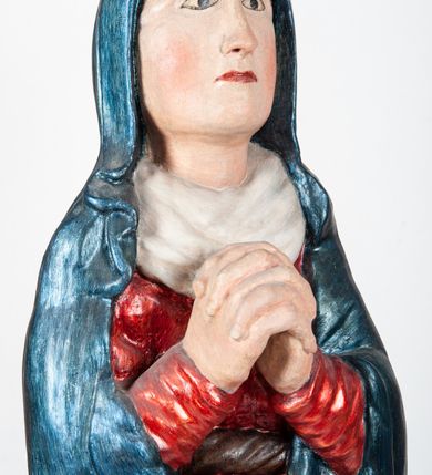 Zdjęcie nr 2: Rzeźba pełnoplastyczna, ukazująca Matkę Boską Bolesną w całej postaci. Matka Boska stoi w lekkim kontrapoście, ciężar ciała wspierając na prawej nodze, z dłońmi splecionymi na wysokości piersi w modlitewnym geście, z głową lekko odchyloną do tyłu i wzrokiem skierowanym ku górze. Twarz potraktowana schematycznie. Maria ubrana w czerwoną suknię przepasaną brązowym sznurem i niebieski płaszcz założony na głowę i barki, podtrzymywany z przodu przedramionami. Wokół szyi biała chusta.
