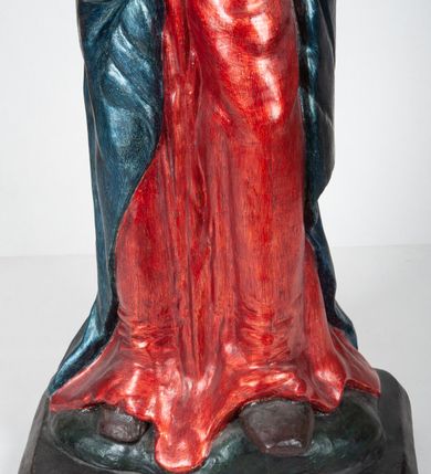 Zdjęcie nr 5: Rzeźba pełnoplastyczna, ukazująca Matkę Boską Bolesną w całej postaci. Matka Boska stoi w lekkim kontrapoście, ciężar ciała wspierając na prawej nodze, z dłońmi splecionymi na wysokości piersi w modlitewnym geście, z głową lekko odchyloną do tyłu i wzrokiem skierowanym ku górze. Twarz potraktowana schematycznie. Maria ubrana w czerwoną suknię przepasaną brązowym sznurem i niebieski płaszcz założony na głowę i barki, podtrzymywany z przodu przedramionami. Wokół szyi biała chusta.