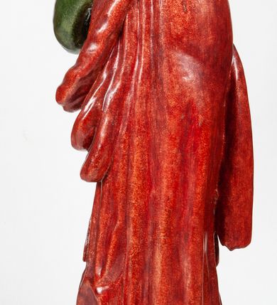 Zdjęcie nr 2: Rzeźba pełnoplastyczna, przedstawiająca św. Jana Ewangelistę w całej postaci. Apostoł stoi w lekkim kontrapoście, ciężar ciała wspierając na lewej nodze, z głową przechyloną na lewy bark. Prawą dłonią, uniesioną na wysokość pasa, podtrzymuje zamkniętą księgę, lewą dłoń przyciska do policzka w geście bólu i rozpaczy. Twarz potraktowana schematycznie, okolona długimi, brązowymi włosami z przedziałkiem pośrodku głowy. Święty ubrany w zieloną, długa tunikę, przewiązaną w pasie sznurem oraz czerwony płaszcz zarzucony na prawy bark i okrywający plecy, z przodu podtrzymywany prawym przedramieniem. Stopy bose.