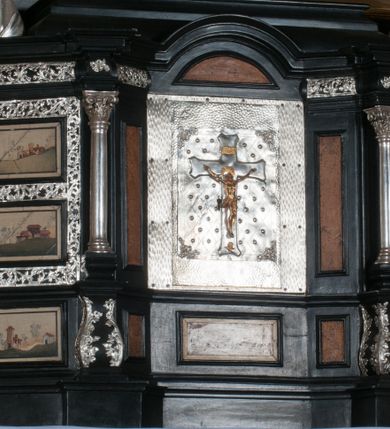 Zdjęcie nr 3: Tabernakulum na rzucie połowy ośmioboku, architektoniczne, na niskim postumencie, trójosiowe, dwudzielne (z wydzieloną gzymsem częścią cokołową), artykułowane kolumienkami o kapitelach kompozytowych oraz wolutami podtrzymującymi kompozytowe kapitele, na wybrzuszonych, zdwojonych cokołach. Belkowanie występujące nad podporami. Ścianka z drzwiczkami zamknięta łukiem półkolistym. Cokoliki, fryz i boczne ścianki tabernakulum zdobione suchym akantem. Drzwiczki jednoskrzydłowe (nowsze, pierwotne dwuskrzydłowe), srebrne, zdobione prostokątną płyciną, z romboidalnymi polami i spłaszczonymi kulami. W narożach stylizowany ornament roślinny. W centrum przedstawienie Chrystusa na krzyżu. Pola bocznych ścianek zdobione imitującymi szufladki mozaikowymi płycinami z różnobarwnych marmurów przedstawiającymi pejzaż z elementami architektury oraz płycinami wykładanymi jasnym drewnem. Pejzażowe płyciny w górnej części tabernakulum ujęte srebrnymi, odlewanymi i cyzelowanym ramkami. 
Na tabernakulum umieszczone antytetycznie rzeźby dwóch aniołów: pełnoplastyczne, w ujęciu całopostaciowym, wolnostojące. Anioł po lewej stronie ukazany jest w pozycji klęczącej, z profilu, pochylony do przodu. W rękach trzyma łódkę na kadzidło. Włosy brązowe, falowane, sięgające do ramion. Twarz pociągła, łukowato wygięte brwi, szeroko otwarte oczy, prosty nos, róż na policzkach. Skrzydła złote. Anioł odziany jest białą tunikę, z krótkimi rękawami i z cienkimi, pionowymi fałdami, załamującymi się na wysokości kolan. Stopy bose. Anioł po prawej ukazany jest w pozycji klęczącej, z profilu, pochylony do przodu. W rękach trzyma trybularz. Włosy brązowe, falowane, sięgające do ramion. Twarz pociągła, łukowato wygięte brwi, szeroko otwarte oczy, prosty nos, róż na policzkach. Skrzydła złote. Anioł odziany jest białą tunikę, z krótkimi rękawami i z cienkimi, pionowymi fałdami, załamującymi się na wysokości kolan. Stopy bose.
