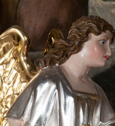 Zdjęcie nr 7: Tabernakulum na rzucie połowy ośmioboku, architektoniczne, na niskim postumencie, trójosiowe, dwudzielne (z wydzieloną gzymsem częścią cokołową), artykułowane kolumienkami o kapitelach kompozytowych oraz wolutami podtrzymującymi kompozytowe kapitele, na wybrzuszonych, zdwojonych cokołach. Belkowanie występujące nad podporami. Ścianka z drzwiczkami zamknięta łukiem półkolistym. Cokoliki, fryz i boczne ścianki tabernakulum zdobione suchym akantem. Drzwiczki jednoskrzydłowe (nowsze, pierwotne dwuskrzydłowe), srebrne, zdobione prostokątną płyciną, z romboidalnymi polami i spłaszczonymi kulami. W narożach stylizowany ornament roślinny. W centrum przedstawienie Chrystusa na krzyżu. Pola bocznych ścianek zdobione imitującymi szufladki mozaikowymi płycinami z różnobarwnych marmurów przedstawiającymi pejzaż z elementami architektury oraz płycinami wykładanymi jasnym drewnem. Pejzażowe płyciny w górnej części tabernakulum ujęte srebrnymi, odlewanymi i cyzelowanym ramkami. 
Na tabernakulum umieszczone antytetycznie rzeźby dwóch aniołów: pełnoplastyczne, w ujęciu całopostaciowym, wolnostojące. Anioł po lewej stronie ukazany jest w pozycji klęczącej, z profilu, pochylony do przodu. W rękach trzyma łódkę na kadzidło. Włosy brązowe, falowane, sięgające do ramion. Twarz pociągła, łukowato wygięte brwi, szeroko otwarte oczy, prosty nos, róż na policzkach. Skrzydła złote. Anioł odziany jest białą tunikę, z krótkimi rękawami i z cienkimi, pionowymi fałdami, załamującymi się na wysokości kolan. Stopy bose. Anioł po prawej ukazany jest w pozycji klęczącej, z profilu, pochylony do przodu. W rękach trzyma trybularz. Włosy brązowe, falowane, sięgające do ramion. Twarz pociągła, łukowato wygięte brwi, szeroko otwarte oczy, prosty nos, róż na policzkach. Skrzydła złote. Anioł odziany jest białą tunikę, z krótkimi rękawami i z cienkimi, pionowymi fałdami, załamującymi się na wysokości kolan. Stopy bose.