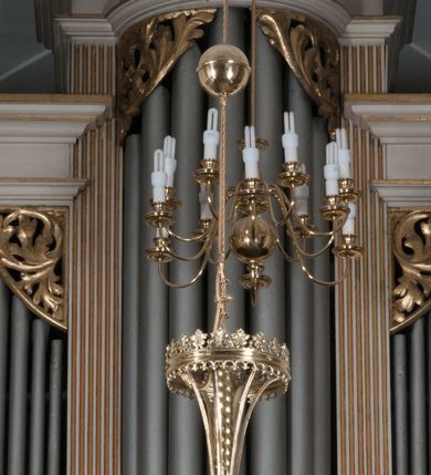 Zdjęcie nr 1: Prospekt architektoniczny, na prostopadłościennym cokole, jednokondygnacyjny, trójosiowy, ze zwieńczeniem. Podziały wewnętrzne wyznaczają kanelowane pilastry wspierające uproszczone belkowanie i gzyms. Część środkowa prospektu występująca półkoliście przed lico, wypiętrzona w stosunku do części skrajnych, zwieńczona rzeźbionym złoconym ornamentem o motywach roślinnych. Pola skrajne prostokątne. Górne naroża otworów na piszczałki wypełnione ażurowymi, złoconymi motywami liści akantu. Struktura malowana na biało, detale architektoniczne i ornamenty złocone. Pierwotnie na narożach złocone wazony. 