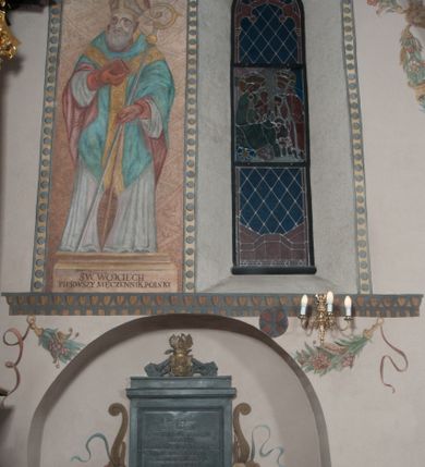 Zdjęcie nr 34: Sklepienie: żebra ozdobione na przemian pasami w kolorach czerwonym i niebieskim. Na gładkich zwornikach malowane tarcze herbowe od wschodu: Gryf i Łabędź. Wysklepki malowane wzdłuż żeber ornamentem geometrycznym złożonym z półkoli, zakończonych liliami heraldycznymi. Ze zworników rozchodzi się wić roślinna.
Ściana północna: przęsło wschodnie - trzy sceny podzielone na dwie strefy, zamknięte arkadami wspartymi na tralkach. W dolnej: klęczący św. Grzegorz, pod arkadą, na tle tkaniny; w kolejnej postać klęczącej kobiety przed sceną zstąpienia Chrystusa do piekieł (?). W górnej strefie św. Grzegorz klęczący przed trzema mężczyznami zgrupowanymi wokół stołu, którzy pokazują świętemu tkaninę. Przęsło zachodnie: scena podzielone na dwie strefy. W dolnej scena wielofiguralna, przedstawiająca ucztę ze św. Grzegorzem z gołębicą na ramieniu, siedzącym po środku stołu, oraz z pochylającym się ku niemu aniołem. Zamykają ją trzy arkady. W górnej scena eucharystyczna ze św. Grzegorzem i diakonem, klęczącymi przed ołtarzem, na którym stoi Chrystus na tle niszy. Całość zamknięta arkadą. Łuk arkady prowadzącej do kruchty podkreślony bordiurą z ornamentem plecionkowym, ujęty kandelabrami dźwigającymi gzyms. W przyłuczach dwie uskrzydlone główki anielskie. Ściana południowa: W obu przęsłach analogicznie do okien malowane iluzjonistyczne nisze konchowe z postaciami świętych na postumentach w górnej strefie ściany. W podłuczach arkad girlandy, podtrzymywane przez uskrzydlone główki anielskie. Nisze i okna obwiedzione bordiurą z ornamentem geometrycznym, podtrzymane wspólnym parapetem z podwieszoną girlandą kwiatową. Pod wspornikiem malowana kolumna utworzona z dwóch tralek. W prześle wschodnim: postać św. Wojciecha, z malowaną na postumencie inskrypcją: ŚW. WOJCIECH / PIERWSZY MĘCZNNIK POLSKI. W przęśle zachodnim: postać św. Stanisława biskupa z półpostacią Piotrowina z prawej strony. Na postumencie malowana inskrypcja: W 700-LECIE KANONIZACJI / ŚW. STANISŁAWA BP-A KRAKOWSKIEGO / 1253 – 1953.W dolnej strefie ściany epitafia ujmuje dekoracja. Epitafium Jacka Konstantyna Chościaka Popiela: stylizowane dekoracja roślinna z falującymi wstęgami; tablica pamiątkowa podtrzymywana przez putta. Łuk tęczowy od strony prezbiterium obwiedziony analogicznym do sklepienia geometrycznym ornamentem. Kolorystyka pastelowa, z silnymi akcentami błękitu, czerwieni i żółcieni.