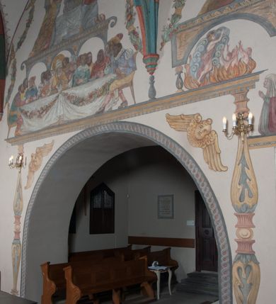 Zdjęcie nr 42: Sklepienie: żebra ozdobione na przemian pasami w kolorach czerwonym i niebieskim. Na gładkich zwornikach malowane tarcze herbowe od wschodu: Gryf i Łabędź. Wysklepki malowane wzdłuż żeber ornamentem geometrycznym złożonym z półkoli, zakończonych liliami heraldycznymi. Ze zworników rozchodzi się wić roślinna.
Ściana północna: przęsło wschodnie - trzy sceny podzielone na dwie strefy, zamknięte arkadami wspartymi na tralkach. W dolnej: klęczący św. Grzegorz, pod arkadą, na tle tkaniny; w kolejnej postać klęczącej kobiety przed sceną zstąpienia Chrystusa do piekieł (?). W górnej strefie św. Grzegorz klęczący przed trzema mężczyznami zgrupowanymi wokół stołu, którzy pokazują świętemu tkaninę. Przęsło zachodnie: scena podzielone na dwie strefy. W dolnej scena wielofiguralna, przedstawiająca ucztę ze św. Grzegorzem z gołębicą na ramieniu, siedzącym po środku stołu, oraz z pochylającym się ku niemu aniołem. Zamykają ją trzy arkady. W górnej scena eucharystyczna ze św. Grzegorzem i diakonem, klęczącymi przed ołtarzem, na którym stoi Chrystus na tle niszy. Całość zamknięta arkadą. Łuk arkady prowadzącej do kruchty podkreślony bordiurą z ornamentem plecionkowym, ujęty kandelabrami dźwigającymi gzyms. W przyłuczach dwie uskrzydlone główki anielskie. Ściana południowa: W obu przęsłach analogicznie do okien malowane iluzjonistyczne nisze konchowe z postaciami świętych na postumentach w górnej strefie ściany. W podłuczach arkad girlandy, podtrzymywane przez uskrzydlone główki anielskie. Nisze i okna obwiedzione bordiurą z ornamentem geometrycznym, podtrzymane wspólnym parapetem z podwieszoną girlandą kwiatową. Pod wspornikiem malowana kolumna utworzona z dwóch tralek. W prześle wschodnim: postać św. Wojciecha, z malowaną na postumencie inskrypcją: ŚW. WOJCIECH / PIERWSZY MĘCZNNIK POLSKI. W przęśle zachodnim: postać św. Stanisława biskupa z półpostacią Piotrowina z prawej strony. Na postumencie malowana inskrypcja: W 700-LECIE KANONIZACJI / ŚW. STANISŁAWA BP-A KRAKOWSKIEGO / 1253 – 1953.W dolnej strefie ściany epitafia ujmuje dekoracja. Epitafium Jacka Konstantyna Chościaka Popiela: stylizowane dekoracja roślinna z falującymi wstęgami; tablica pamiątkowa podtrzymywana przez putta. Łuk tęczowy od strony prezbiterium obwiedziony analogicznym do sklepienia geometrycznym ornamentem. Kolorystyka pastelowa, z silnymi akcentami błękitu, czerwieni i żółcieni.