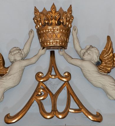 Zdjęcie nr 5: Nastawa niearchitektoniczna. Ołtarz prostopadłościenny, kamienny, z drewnianą mensą. Antepedium dekorowane trzema kwadratowymi polami wypełnionymi geometryczną mozaiką w formie krzyży o rozszerzających się ramionach. Na ołtarzu tabernakulum w formie prostopadłościennej skrzynki, obitej blachą, o zaokrąglonych narożach. Drzwiczki w kształcie stojącego prostokąta zamkniętego łukiem półkolistym nadwieszonym, z przedstawieniem kielicha z hostią w glorii. Na ściance frontowej aplikowana dekoracja w postaci kłosów zbóż i winnego grona. Tron wystawienia w formie baldachimu podtrzymywanego na czterech tralkach. Obraz Matki Boskiej Częstochowskiej w kształcie stojącego prostokąta, ujęty grubą, złoconą ramą dekorowaną ornamentem z lilii heraldycznych. Dzieło flankowane jest dwiema postaciami klęczących aniołów, podtrzymujących je obiema rękami. Anioły ukazane z profilu, lewy z głową skierowaną frontalnie. Ubrane są w luźne tuniki przepasane w talii. Skrzydła mają duże, złożone, wygięte na kształt litery „C”. Nad obrazem monogram Marii, flankowany przez dwa putta podtrzymujące nad nim koronę otwartą. Postacie polichromowane są na biało, o złoconych skrzydłach. 

