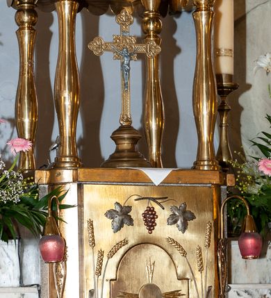 Zdjęcie nr 4: Nastawa niearchitektoniczna. Ołtarz prostopadłościenny, kamienny, z drewnianą mensą. Antepedium dekorowane trzema kwadratowymi polami wypełnionymi geometryczną mozaiką w formie krzyży o rozszerzających się ramionach. Na ołtarzu tabernakulum w formie prostopadłościennej skrzynki, obitej blachą, o zaokrąglonych narożach. Drzwiczki w kształcie stojącego prostokąta zamkniętego łukiem półkolistym nadwieszonym, z przedstawieniem kielicha z hostią w glorii. Na ściance frontowej aplikowana dekoracja w postaci kłosów zbóż i winnego grona. Tron wystawienia w formie baldachimu podtrzymywanego na czterech tralkach. Obraz Matki Boskiej Częstochowskiej w kształcie stojącego prostokąta, ujęty grubą, złoconą ramą dekorowaną ornamentem z lilii heraldycznych. Dzieło flankowane jest dwiema postaciami klęczących aniołów, podtrzymujących je obiema rękami. Anioły ukazane z profilu, lewy z głową skierowaną frontalnie. Ubrane są w luźne tuniki przepasane w talii. Skrzydła mają duże, złożone, wygięte na kształt litery „C”. Nad obrazem monogram Marii, flankowany przez dwa putta podtrzymujące nad nim koronę otwartą. Postacie polichromowane są na biało, o złoconych skrzydłach. 

