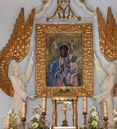 Zdjęcie nr 1: Nastawa niearchitektoniczna. Ołtarz prostopadłościenny, kamienny, z drewnianą mensą. Antepedium dekorowane trzema kwadratowymi polami wypełnionymi geometryczną mozaiką w formie krzyży o rozszerzających się ramionach. Na ołtarzu tabernakulum w formie prostopadłościennej skrzynki, obitej blachą, o zaokrąglonych narożach. Drzwiczki w kształcie stojącego prostokąta zamkniętego łukiem półkolistym nadwieszonym, z przedstawieniem kielicha z hostią w glorii. Na ściance frontowej aplikowana dekoracja w postaci kłosów zbóż i winnego grona. Tron wystawienia w formie baldachimu podtrzymywanego na czterech tralkach. Obraz Matki Boskiej Częstochowskiej w kształcie stojącego prostokąta, ujęty grubą, złoconą ramą dekorowaną ornamentem z lilii heraldycznych. Dzieło flankowane jest dwiema postaciami klęczących aniołów, podtrzymujących je obiema rękami. Anioły ukazane z profilu, lewy z głową skierowaną frontalnie. Ubrane są w luźne tuniki przepasane w talii. Skrzydła mają duże, złożone, wygięte na kształt litery „C”. Nad obrazem monogram Marii, flankowany przez dwa putta podtrzymujące nad nim koronę otwartą. Postacie polichromowane są na biało, o złoconych skrzydłach. 

