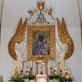 Zdjęcie nr 1: Nastawa niearchitektoniczna. Ołtarz prostopadłościenny, kamienny, z drewnianą mensą. Antepedium dekorowane trzema kwadratowymi polami wypełnionymi geometryczną mozaiką w formie krzyży o rozszerzających się ramionach. Na ołtarzu tabernakulum w formie prostopadłościennej skrzynki, obitej blachą, o zaokrąglonych narożach. Drzwiczki w kształcie stojącego prostokąta zamkniętego łukiem półkolistym nadwieszonym, z przedstawieniem kielicha z hostią w glorii. Na ściance frontowej aplikowana dekoracja w postaci kłosów zbóż i winnego grona. Tron wystawienia w formie baldachimu podtrzymywanego na czterech tralkach. Obraz Matki Boskiej Częstochowskiej w kształcie stojącego prostokąta, ujęty grubą, złoconą ramą dekorowaną ornamentem z lilii heraldycznych. Dzieło flankowane jest dwiema postaciami klęczących aniołów, podtrzymujących je obiema rękami. Anioły ukazane z profilu, lewy z głową skierowaną frontalnie. Ubrane są w luźne tuniki przepasane w talii. Skrzydła mają duże, złożone, wygięte na kształt litery „C”. Nad obrazem monogram Marii, flankowany przez dwa putta podtrzymujące nad nim koronę otwartą. Postacie polichromowane są na biało, o złoconych skrzydłach. 

