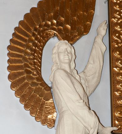 Zdjęcie nr 10: Nastawa niearchitektoniczna. Ołtarz prostopadłościenny, kamienny, z drewnianą mensą. Antepedium dekorowane trzema kwadratowymi polami wypełnionymi geometryczną mozaiką w formie krzyży o rozszerzających się ramionach. Na ołtarzu tabernakulum w formie prostopadłościennej skrzynki, obitej blachą, o zaokrąglonych narożach. Drzwiczki w kształcie stojącego prostokąta zamkniętego łukiem półkolistym nadwieszonym, z przedstawieniem kielicha z hostią w glorii. Na ściance frontowej aplikowana dekoracja w postaci kłosów zbóż i winnego grona. Tron wystawienia w formie baldachimu podtrzymywanego na czterech tralkach. Obraz Matki Boskiej Częstochowskiej w kształcie stojącego prostokąta, ujęty grubą, złoconą ramą dekorowaną ornamentem z lilii heraldycznych. Dzieło flankowane jest dwiema postaciami klęczących aniołów, podtrzymujących je obiema rękami. Anioły ukazane z profilu, lewy z głową skierowaną frontalnie. Ubrane są w luźne tuniki przepasane w talii. Skrzydła mają duże, złożone, wygięte na kształt litery „C”. Nad obrazem monogram Marii, flankowany przez dwa putta podtrzymujące nad nim koronę otwartą. Postacie polichromowane są na biało, o złoconych skrzydłach. 

