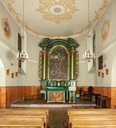 Zdjęcie nr 2: Ołtarz przyścienny, architektoniczny, jednoosiowy, jednokondygnacyjny, z uszakami. Mensa prostopadłościenna. Na niej prostopadłościenne tabernakulum zwieńczone wydatnym gzymsem, z drzwiczkami zamkniętymi łukiem nadwieszonym z motywem kielicha z hostią. Nastawa ołtarzowa ujęta korynckimi kolumnami ustawionymi na podwójnym cokole zdobionym prostokątnymi płycinami w dolnej partii i plakietami utworzonymi z ornamentu małżowinowo-chrząstkowego w górnej. Podpory dźwigają pełne, wyłamane na ich osiach belkowanie, którego gzyms jest wyniesiony nad polem centralnym. Fryz wysuniętych części dekorowany rozetami, silnie wystający gzyms zdobiony wałeczkami. Na wyłamanych częściach belkowania ustawiono symetrycznie woluty. W polu nisza zamknięta łukiem półkolistym nadwieszonym mieszcząca obraz z wielopostaciową sceną Ukrzyżowania w profilowanej ramie dekorowanej w trzech miejscach ornamentem roślinnym. Kondygnacja ujęta ażurowymi uszakami utworzonymi z suchej wici akantu. Struktura ołtarza w kolorze zielonym, trzony kolumn, detale i ornamenty złocone.
