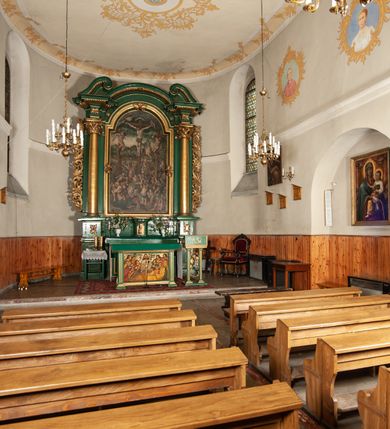 Zdjęcie nr 3: Ołtarz przyścienny, architektoniczny, jednoosiowy, jednokondygnacyjny, z uszakami. Mensa prostopadłościenna. Na niej prostopadłościenne tabernakulum zwieńczone wydatnym gzymsem, z drzwiczkami zamkniętymi łukiem nadwieszonym z motywem kielicha z hostią. Nastawa ołtarzowa ujęta korynckimi kolumnami ustawionymi na podwójnym cokole zdobionym prostokątnymi płycinami w dolnej partii i plakietami utworzonymi z ornamentu małżowinowo-chrząstkowego w górnej. Podpory dźwigają pełne, wyłamane na ich osiach belkowanie, którego gzyms jest wyniesiony nad polem centralnym. Fryz wysuniętych części dekorowany rozetami, silnie wystający gzyms zdobiony wałeczkami. Na wyłamanych częściach belkowania ustawiono symetrycznie woluty. W polu nisza zamknięta łukiem półkolistym nadwieszonym mieszcząca obraz z wielopostaciową sceną Ukrzyżowania w profilowanej ramie dekorowanej w trzech miejscach ornamentem roślinnym. Kondygnacja ujęta ażurowymi uszakami utworzonymi z suchej wici akantu. Struktura ołtarza w kolorze zielonym, trzony kolumn, detale i ornamenty złocone.