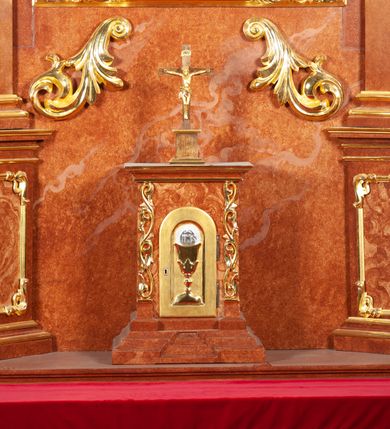 Zdjęcie nr 6: Ołtarz architektoniczny, jednoosiowy, jednokondygnacyjny ze zwieńczeniem, na podwójnym cokole. Mensa prostopadłościenna z antepedium dekorowanym płaskorzeźbionym przedstawieniem baranka Bożego leżącego na księdze i trzymającego krzyż. Na mensie tabernakulum w formie prostopadłościanu na uskokowym cokole. Na ścianie frontowej drzwi w kształcie stojącego prostokąta zamkniętego łukiem pełnym dekorowane kielichem z hostią i ujęte wicią roślinną; kondygnację wieńczy belkowanie oraz krucyfiks. Oś nastawy flankują kolumny i opilastrowane filary o kapitelach kompozytowych, ustawionych ukośnie względem lica ołtarza. W polu środkowym zamknięta półkoliście nisza dekorowana krzyżami, wypełniona rzeźbą Najświętszego Serca Jezusa. U spodu symetrycznie liście akantu. Kolumny dźwigają wyłamane belkowanie, przerwane w partii środkowej, na zewnętrznych podporach woluty, na których posadowiono figurki aniołków. Fantazyjne zwieńczenie w formie zbliżonej do stojącego prostokąta, w którym obraz z przedstawieniem widzenia św. Małgorzaty Marii Alacoque ujęty ramą utworzoną z ornamentu rocaille’owego i wstęgi, zwieńczony muszlą. 
Cokoły podpór dekorowane płycinami, trzony pilastrów ornamentem roślinnym, w partii fryzu rozety. Struktura polichromowana na kolor brązowy, ze złoconą ornamentyką i złoconymi detalami.