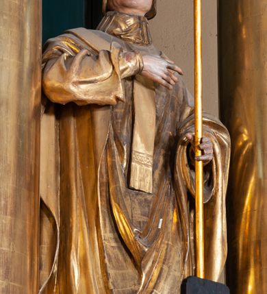 Zdjęcie nr 2: Figura ścięta z tyłu, na cokole. Święty Stanisław został ukazany w pozycji stojącej z głową lekko uniesioną, prawą ręką na wysokości piersi i trzymając pastorał w lewej. Twarz ma pociągłą, brwi wąskie, oczy szeroko otwarte, nos prosty, wąski. Jest ubrany w sutannę, komżę oraz ornat, który spływa w stronę ziemi spokojnymi fałdami oraz stułę i paliusz; na głowie ma infułę. Polichromia w partiach ciała naturalistyczna, szaty i atrybuty złocone.