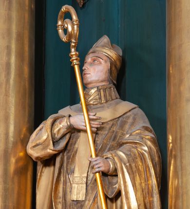 Zdjęcie nr 1: Figura ścięta z tyłu, na cokole. Święty Stanisław został ukazany w pozycji stojącej z głową lekko uniesioną, prawą ręką na wysokości piersi i trzymając pastorał w lewej. Twarz ma pociągłą, brwi wąskie, oczy szeroko otwarte, nos prosty, wąski. Jest ubrany w sutannę, komżę oraz ornat, który spływa w stronę ziemi spokojnymi fałdami oraz stułę i paliusz; na głowie ma infułę. Polichromia w partiach ciała naturalistyczna, szaty i atrybuty złocone.