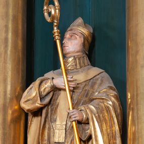 Zdjęcie nr 1: Figura ścięta z tyłu, na cokole. Święty Stanisław został ukazany w pozycji stojącej z głową lekko uniesioną, prawą ręką na wysokości piersi i trzymając pastorał w lewej. Twarz ma pociągłą, brwi wąskie, oczy szeroko otwarte, nos prosty, wąski. Jest ubrany w sutannę, komżę oraz ornat, który spływa w stronę ziemi spokojnymi fałdami oraz stułę i paliusz; na głowie ma infułę. Polichromia w partiach ciała naturalistyczna, szaty i atrybuty złocone.