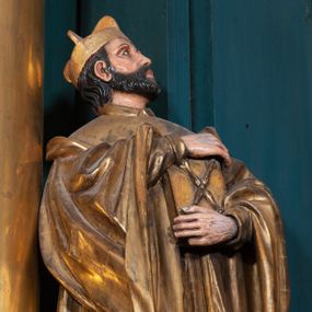 Zdjęcie nr 1: Rzeźba ścięta z tyłu, na cokole, przedstawiająca św. Jana Kantego ukazanego w całej postaci, zwróconego nieznacznie w lewo. Święty obiema rękami przyciska do ciała zamkniętą księgę ze skrzyżowanymi berłami, godłem Uniwersytetu Krakowskiego na okładce. Spogląda w górę, ma owalną, szczupłą twarz z dużymi, szeroko otwartymi oczami i prostym nosem, okalają ją ciemnobrązowe, krótkie, zaczesane do tyłu włosy. Święty ma krótką brodę oraz wąsy. Jest ubrany w obszerną togę uniwersytecką z szerokimi rękawami, które sięgają ud. Na głowie ma biret. Tkanina płaszcza spływa do ziemi podłużnymi, równoległymi fałdami. W partiach ciała polichromia naturalistyczna, płaszcz i atrybuty złocone.