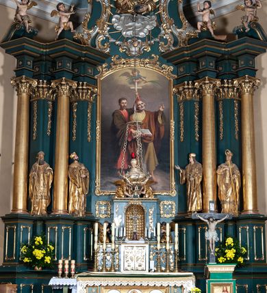 Zdjęcie nr 3: Obraz w formie stojącego prostokąta zamkniętego łukiem odcinkowym. W centrum kompozycji dwie męskie postacie, zwrócone w trzech czwartych w lewo, stojące jedna za drugą. Z przodu św. Szymon z piłą, prawą ręką podtrzymuje księgę, lewą wznosi ku górze, tam też kieruje wzrok. Stojący z tyłu św. Juda palcem prawej ręki wskazuje na księgę, lewą, z krzyżem, unosi ponad nimi. Szymon ubrany jest w żółtą tunikę i brązowy płaszcz, zaś Juda w czerwoną tunikę i zielony płaszcz. Ponad nimi, z jasnożółtych obłoków wyłania się anioł w czerwono-niebieskiej sukni, który trzyma dwie palmy męczeństwa. Święci stoją na boso na ziemi, w lewym dolnym rogu kompozycji, obok stóp św. Judy leży kątownik i strzały. Tło przedstawienia ciemne, rozjaśnia się ku górze. 