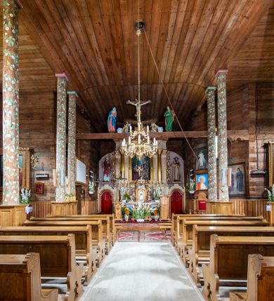 Zdjęcie nr 13: Nastawa ołtarzowa architektoniczna, jednoosiowa z bramkami, jednokondygnacyjna. Ołtarz drewniany, prostopadłościenny. Mensa drewniana z silnie wysuniętym, profilowanym brzegiem. Antependium ujęte grubą ramą, w polu obraz w formie wydłużonego, leżącego prostokąta z przedstawieniem Chrztu Chrystusa. 
Tabernakulum w formie dużej, prostopadłościennej skrzynki ujętej w przednich narożach pilastrami dźwigającymi profilowany, trójbocznie wyłamany gzyms, dekorowany u spodu kostkowaniem i uskrzydloną główką anielską u szczytu. Drzwiczki w formie stojącego prostokąta zamkniętego łukiem półkolistym, ujęte opaską i rzeźbioną ramą; w polu medalion w glorii promienistej z płaskorzeźbioną postacią Dzieciątka na obłoku. Drzwiczki ujęte podwieszonymi na wstędze festonami utworzonymi z winnego grona, kłosów zbóż i kampanuli. Tabernakulum flankowane uszami z karbowanych wolut i liści palmowych; zwieńczone cokołem, na którym stoi równoramienny krzyż o trójlistnym zakończeniu ramion, na ich skrzyżowaniu medalion z Okiem Opatrzności w glorii. Na gzymsie, na osi pilastrów dwie klęczące figury adorujących aniołów. Przed tabernakulum druga para klęczących aniołów trzymających kwieciste girlandy.

Retabulum na wysokim cokole zryzalitowanym przy brzegach; ujęte parą zwielokrotnionych pilastrów o kanelowanych trzonach i stojącą przed nimi parą kolumn o kapitelach kompozytowych. Podpory dźwigają pełne belkowanie, wyłamane na ich osi, przerwane glorią nad polem środkowym oraz przerwany falisty przyczółek. W polu środkowym płytka nisza w formie stojącego prostokąta o wklęsłych górnych narożach, ujęta profilowaną ramą z obrazem Święta Rodzina. Na zasuwie obrazy: Mistyczne Zaślubiny Św. Katarzyny oraz  Najświętsza Maria Panna Niepokalanie Poczęta. W polu belkowania gloria promienista, w której centrum rzeźbione przedstawienie Baranka Apokaliptycznego na księdze, w otoczeniu obłoków, nad nim Gołębica Ducha Świętego; u spodu flankowana dwoma rzeźbami puttów. Bramki z przejściami w formie stojącego prostokąta zamkniętego łukiem półkolistym nadwieszonym, ujęte profilowanymi ramami. Ponad szczyty o fantazyjnym wykroju, tworzące postumenty dla figur św. Augustyna po lewej stronie i św. Hieronima po prawej. Cokół i ryzality dekorowane płycinami, od frontu z ornamentem roślinnym. Rama dekorowana trzema muszlami; w przyłuczach uskrzydlone główki anielskie. W partii fryzu, na osi kolumn rozety. Kondygnacja ujęta uszami utworzonymi z suchego akantu. Struktura polichromowana w kolorze beżowym, detal na czerwono, kolumny, gloria, ornamentyka i profile złocone.