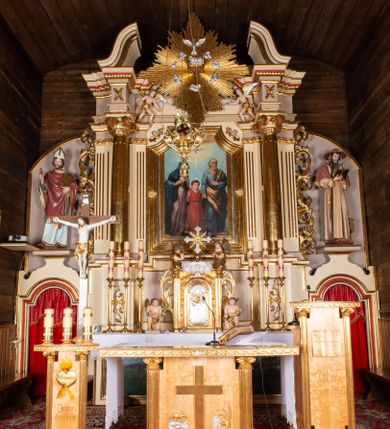 Zdjęcie nr 1: Nastawa ołtarzowa architektoniczna, jednoosiowa z bramkami, jednokondygnacyjna. Ołtarz drewniany, prostopadłościenny. Mensa drewniana z silnie wysuniętym, profilowanym brzegiem. Antependium ujęte grubą ramą, w polu obraz w formie wydłużonego, leżącego prostokąta z przedstawieniem Chrztu Chrystusa. 
Tabernakulum w formie dużej, prostopadłościennej skrzynki ujętej w przednich narożach pilastrami dźwigającymi profilowany, trójbocznie wyłamany gzyms, dekorowany u spodu kostkowaniem i uskrzydloną główką anielską u szczytu. Drzwiczki w formie stojącego prostokąta zamkniętego łukiem półkolistym, ujęte opaską i rzeźbioną ramą; w polu medalion w glorii promienistej z płaskorzeźbioną postacią Dzieciątka na obłoku. Drzwiczki ujęte podwieszonymi na wstędze festonami utworzonymi z winnego grona, kłosów zbóż i kampanuli. Tabernakulum flankowane uszami z karbowanych wolut i liści palmowych; zwieńczone cokołem, na którym stoi równoramienny krzyż o trójlistnym zakończeniu ramion, na ich skrzyżowaniu medalion z Okiem Opatrzności w glorii. Na gzymsie, na osi pilastrów dwie klęczące figury adorujących aniołów. Przed tabernakulum druga para klęczących aniołów trzymających kwieciste girlandy.

Retabulum na wysokim cokole zryzalitowanym przy brzegach; ujęte parą zwielokrotnionych pilastrów o kanelowanych trzonach i stojącą przed nimi parą kolumn o kapitelach kompozytowych. Podpory dźwigają pełne belkowanie, wyłamane na ich osi, przerwane glorią nad polem środkowym oraz przerwany falisty przyczółek. W polu środkowym płytka nisza w formie stojącego prostokąta o wklęsłych górnych narożach, ujęta profilowaną ramą z obrazem Święta Rodzina. Na zasuwie obrazy: Mistyczne Zaślubiny Św. Katarzyny oraz  Najświętsza Maria Panna Niepokalanie Poczęta. W polu belkowania gloria promienista, w której centrum rzeźbione przedstawienie Baranka Apokaliptycznego na księdze, w otoczeniu obłoków, nad nim Gołębica Ducha Świętego; u spodu flankowana dwoma rzeźbami puttów. Bramki z przejściami w formie stojącego prostokąta zamkniętego łukiem półkolistym nadwieszonym, ujęte profilowanymi ramami. Ponad szczyty o fantazyjnym wykroju, tworzące postumenty dla figur św. Augustyna po lewej stronie i św. Hieronima po prawej. Cokół i ryzality dekorowane płycinami, od frontu z ornamentem roślinnym. Rama dekorowana trzema muszlami; w przyłuczach uskrzydlone główki anielskie. W partii fryzu, na osi kolumn rozety. Kondygnacja ujęta uszami utworzonymi z suchego akantu. Struktura polichromowana w kolorze beżowym, detal na czerwono, kolumny, gloria, ornamentyka i profile złocone.