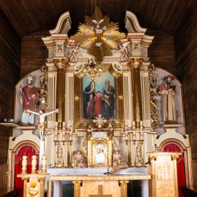 Zdjęcie nr 1: Nastawa ołtarzowa architektoniczna, jednoosiowa z bramkami, jednokondygnacyjna. Ołtarz drewniany, prostopadłościenny. Mensa drewniana z silnie wysuniętym, profilowanym brzegiem. Antependium ujęte grubą ramą, w polu obraz w formie wydłużonego, leżącego prostokąta z przedstawieniem Chrztu Chrystusa. 
Tabernakulum w formie dużej, prostopadłościennej skrzynki ujętej w przednich narożach pilastrami dźwigającymi profilowany, trójbocznie wyłamany gzyms, dekorowany u spodu kostkowaniem i uskrzydloną główką anielską u szczytu. Drzwiczki w formie stojącego prostokąta zamkniętego łukiem półkolistym, ujęte opaską i rzeźbioną ramą; w polu medalion w glorii promienistej z płaskorzeźbioną postacią Dzieciątka na obłoku. Drzwiczki ujęte podwieszonymi na wstędze festonami utworzonymi z winnego grona, kłosów zbóż i kampanuli. Tabernakulum flankowane uszami z karbowanych wolut i liści palmowych; zwieńczone cokołem, na którym stoi równoramienny krzyż o trójlistnym zakończeniu ramion, na ich skrzyżowaniu medalion z Okiem Opatrzności w glorii. Na gzymsie, na osi pilastrów dwie klęczące figury adorujących aniołów. Przed tabernakulum druga para klęczących aniołów trzymających kwieciste girlandy.

Retabulum na wysokim cokole zryzalitowanym przy brzegach; ujęte parą zwielokrotnionych pilastrów o kanelowanych trzonach i stojącą przed nimi parą kolumn o kapitelach kompozytowych. Podpory dźwigają pełne belkowanie, wyłamane na ich osi, przerwane glorią nad polem środkowym oraz przerwany falisty przyczółek. W polu środkowym płytka nisza w formie stojącego prostokąta o wklęsłych górnych narożach, ujęta profilowaną ramą z obrazem Święta Rodzina. Na zasuwie obrazy: Mistyczne Zaślubiny Św. Katarzyny oraz  Najświętsza Maria Panna Niepokalanie Poczęta. W polu belkowania gloria promienista, w której centrum rzeźbione przedstawienie Baranka Apokaliptycznego na księdze, w otoczeniu obłoków, nad nim Gołębica Ducha Świętego; u spodu flankowana dwoma rzeźbami puttów. Bramki z przejściami w formie stojącego prostokąta zamkniętego łukiem półkolistym nadwieszonym, ujęte profilowanymi ramami. Ponad szczyty o fantazyjnym wykroju, tworzące postumenty dla figur św. Augustyna po lewej stronie i św. Hieronima po prawej. Cokół i ryzality dekorowane płycinami, od frontu z ornamentem roślinnym. Rama dekorowana trzema muszlami; w przyłuczach uskrzydlone główki anielskie. W partii fryzu, na osi kolumn rozety. Kondygnacja ujęta uszami utworzonymi z suchego akantu. Struktura polichromowana w kolorze beżowym, detal na czerwono, kolumny, gloria, ornamentyka i profile złocone.