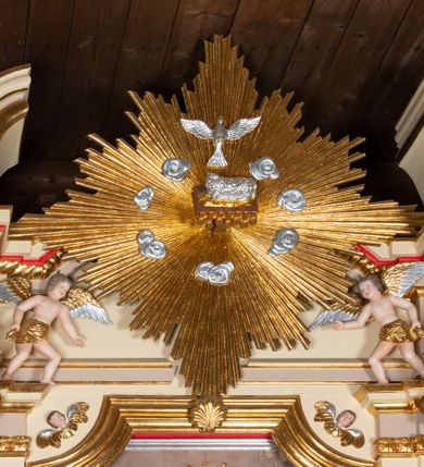 Zdjęcie nr 15: Nastawa ołtarzowa architektoniczna, jednoosiowa z bramkami, jednokondygnacyjna. Ołtarz drewniany, prostopadłościenny. Mensa drewniana z silnie wysuniętym, profilowanym brzegiem. Antependium ujęte grubą ramą, w polu obraz w formie wydłużonego, leżącego prostokąta z przedstawieniem Chrztu Chrystusa. 
Tabernakulum w formie dużej, prostopadłościennej skrzynki ujętej w przednich narożach pilastrami dźwigającymi profilowany, trójbocznie wyłamany gzyms, dekorowany u spodu kostkowaniem i uskrzydloną główką anielską u szczytu. Drzwiczki w formie stojącego prostokąta zamkniętego łukiem półkolistym, ujęte opaską i rzeźbioną ramą; w polu medalion w glorii promienistej z płaskorzeźbioną postacią Dzieciątka na obłoku. Drzwiczki ujęte podwieszonymi na wstędze festonami utworzonymi z winnego grona, kłosów zbóż i kampanuli. Tabernakulum flankowane uszami z karbowanych wolut i liści palmowych; zwieńczone cokołem, na którym stoi równoramienny krzyż o trójlistnym zakończeniu ramion, na ich skrzyżowaniu medalion z Okiem Opatrzności w glorii. Na gzymsie, na osi pilastrów dwie klęczące figury adorujących aniołów. Przed tabernakulum druga para klęczących aniołów trzymających kwieciste girlandy.

Retabulum na wysokim cokole zryzalitowanym przy brzegach; ujęte parą zwielokrotnionych pilastrów o kanelowanych trzonach i stojącą przed nimi parą kolumn o kapitelach kompozytowych. Podpory dźwigają pełne belkowanie, wyłamane na ich osi, przerwane glorią nad polem środkowym oraz przerwany falisty przyczółek. W polu środkowym płytka nisza w formie stojącego prostokąta o wklęsłych górnych narożach, ujęta profilowaną ramą z obrazem Święta Rodzina. Na zasuwie obrazy: Mistyczne Zaślubiny Św. Katarzyny oraz  Najświętsza Maria Panna Niepokalanie Poczęta. W polu belkowania gloria promienista, w której centrum rzeźbione przedstawienie Baranka Apokaliptycznego na księdze, w otoczeniu obłoków, nad nim Gołębica Ducha Świętego; u spodu flankowana dwoma rzeźbami puttów. Bramki z przejściami w formie stojącego prostokąta zamkniętego łukiem półkolistym nadwieszonym, ujęte profilowanymi ramami. Ponad szczyty o fantazyjnym wykroju, tworzące postumenty dla figur św. Augustyna po lewej stronie i św. Hieronima po prawej. Cokół i ryzality dekorowane płycinami, od frontu z ornamentem roślinnym. Rama dekorowana trzema muszlami; w przyłuczach uskrzydlone główki anielskie. W partii fryzu, na osi kolumn rozety. Kondygnacja ujęta uszami utworzonymi z suchego akantu. Struktura polichromowana w kolorze beżowym, detal na czerwono, kolumny, gloria, ornamentyka i profile złocone.