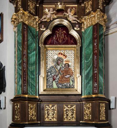 Zdjęcie nr 1: Ołtarz boczny, ustawiony w południowo-wschodnim narożu korpus, jest architektoniczny, jednokondygnacyjny, jednoosiowy ze zwieńczeniem. Sam ołtarz z prostą mensą jest prostopadłościenny. Retabulum zostało zbudowane na zdwojonym cokole, ustawionym ukośnie, z filarami opiętymi z trzech stron pilastrami kompozytowymi podtrzymującymi belkowanie o znacznie wysuniętym gzymsie. Zwieńczenie jest w kształcie stojącego prostokąta ujętego ukośnie dostawionymi spływami wolutowymi dźwigającymi odcinki belkowania z silnie wyłamanym ku przodowi gzymsem z muszlą palmetową pośrodku. Na cokołach i w partii fryzu znajdują się wstęgi ornamentu regencyjnego z listkami i rozetami, a w zwieńczeniu kampanule podwieszone pod listkami akantu. W części środkowej wnęka ujęta w profilowaną ramę, prostokątną, z uszkami u dołu, zakończoną trójliściem, w której jest umieszczony obraz Matki Boskiej z Dzieciątkiem (na zasuwie obraz z przedstawieniem św. Józefa); nad ramą para uskrzydlonych aniołków podtrzymujących koronę otwartą z wydatnymi fleuronami. Na belkowaniu siedzą uskrzydlone aniołki, przepasane opaską na biodrach, z narzędziami Męki Pańskiej w rękach. W zwieńczeniu o formie prostokąta zamkniętego łukiem półkolistym, nadwieszonym, w profilowanej ramie, znajduje się obraz ukazujący św. Marię Magdalenę. Ołtarz polichromowany na ciemny brąz, z filarami i pilastrami imitującymi marmoryzację, ze złoconymi ornamentami i profilami; figury aniołów z naturalną karnacją, ze złoconymi skrzydłami. Polichromia ołtarza w tonacji brązowej i zielonej ze złoceniami. 



