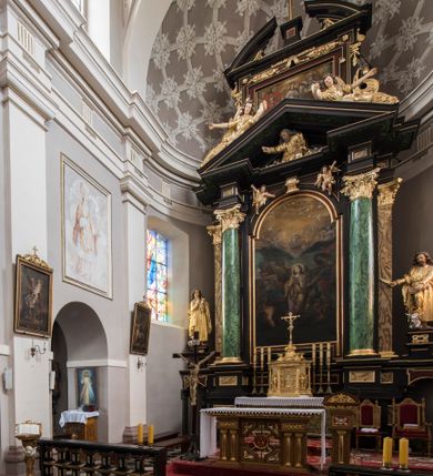 Zdjęcie nr 5: Ołtarz architektoniczny, jednoosiowy, jednokondygnacyjny ze zwieńczeniem. Nastawa jest osadzona na wysokim cokole zdobionym płycinami, ujęta bramkami z prześwitami prostokątnymi zakończonymi półkoliście. Część środkowa ołtarza jest ujęta kompozytowymi kolumnami i cofniętymi do tyłu filarami podtrzymującymi wyłamujące się ponad nimi odcinki belkowania z wspólnym, silnie wysuniętym gzymsem, ponad którym znajduje się trójkątny przyczółek. Zwieńczenie prostokątne, w profilowanej ramie z uszakami, zakończone przerwanym przyczółkiem, wewnątrz którego krzyż na postumencie. Nad bramkami posadowione figury św. Jana z orłem u stóp, kielichem i wężem w dłoni oraz św. Łukasza z wołem u stóp, księgą i piórem w ręku. Pod belkowaniem wkomponowano dwa uskrzydlone putta, w przyczółku figurę ukazanego do pasa Boga Ojca w chmurach, z prawą ręką uniesioną w geście błogosławieństwa, z lewą spoczywającą na globie, a na przyczółku leżące figury uskrzydlonych aniołów. W polu głównym jest obraz „Męczeństwo św. Katarzyny”, w zwieńczeniu obraz „Koronacja Marii”. 

