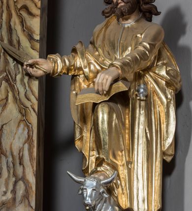 Zdjęcie nr 11: Ołtarz architektoniczny, jednoosiowy, jednokondygnacyjny ze zwieńczeniem. Nastawa jest osadzona na wysokim cokole zdobionym płycinami, ujęta bramkami z prześwitami prostokątnymi zakończonymi półkoliście. Część środkowa ołtarza jest ujęta kompozytowymi kolumnami i cofniętymi do tyłu filarami podtrzymującymi wyłamujące się ponad nimi odcinki belkowania z wspólnym, silnie wysuniętym gzymsem, ponad którym znajduje się trójkątny przyczółek. Zwieńczenie prostokątne, w profilowanej ramie z uszakami, zakończone przerwanym przyczółkiem, wewnątrz którego krzyż na postumencie. Nad bramkami posadowione figury św. Jana z orłem u stóp, kielichem i wężem w dłoni oraz św. Łukasza z wołem u stóp, księgą i piórem w ręku. Pod belkowaniem wkomponowano dwa uskrzydlone putta, w przyczółku figurę ukazanego do pasa Boga Ojca w chmurach, z prawą ręką uniesioną w geście błogosławieństwa, z lewą spoczywającą na globie, a na przyczółku leżące figury uskrzydlonych aniołów. W polu głównym jest obraz „Męczeństwo św. Katarzyny”, w zwieńczeniu obraz „Koronacja Marii”. 


