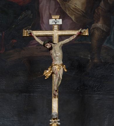 Zdjęcie nr 11: Tabernakulum w formie sześcianu, na niskim cokole, z dwukolumnowym portykiem utworzonym z pilastrów toskańskich i kolumn kompozytowych od frontu i dwóch analogicznych kolumn na tle pilastrów po bokach podtrzymujących przełamujące się na nimi belkowanie. Kolumny osadzone na niskich piedestałach, lekko wybrzuszonych, otoczonych liśćmi akantu. Kolumny pokryte symetrycznie układającymi i przeplatającymi się wokół pionowego trzpienia liśćmi i zwieńczone jońskimi kapitelami. Fryz belkowania zdobiony uskrzydloną główką aniołka, liściastymi wolutami, rautami w drobnych kartuszach i kostkowaniem. Drzwi tabernakulum zdobione są płaskorzeźbionym kielichem z hostią. Po bokach wypukło rzeźbione główki anielskie, a nad nimi okrągły medalion z literami IHS obwiedziony wieńcem laurowym, z elementami przechodzących między sobą listw kartuszowych i podwieszonych pod nie festonów. W ściankach naroży tabernakulum cztery nisze konchowe z muszlami wypełnione figurkami świętych. Jeden w wielbłądziej skórze trzymający księgę z barankiem przedstawia św. Jana Chrzciciela. Trzej pozostali są trudni do identyfikacji. Jeden trzyma otwartą księgę, a u jego stóp widnieje mitra książęca, drugi trzyma pastorał a u jego stóp leży infuła, trzeci z laską i kapeluszem u stóp (św. Jakub?). 


