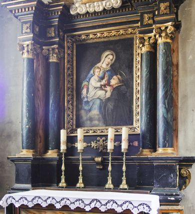 Zdjęcie nr 2: Prostopadłościenny ołtarz z retabulum posadowionym na dwustrefowym cokole. Nastawa ujęta parami kolumn, z których zewnętrzne są wysunięte do przodu, a środkowe cofnięte do tyłu, z kapitelami kompozytowymi, podtrzymującymi przełamujące się nad nimi belkowanie, z wydatnym gzymsem ozdobionym kostkowaniem. Na osi kolumn skrajnych faliste naczółki, nad częścią środkową Oko Opatrzności obramione chmurami, na tle promienistej glorii. Pośrodku nastawy prostokątny obraz w profilowanej ramie wypełnionej kwiatonami z wyobrażeniem Matki Boskiej Różańcowej i św. Dominikiem. 

