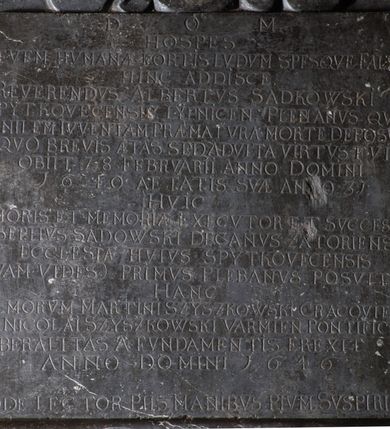 Zdjęcie nr 11: Tablica epitafijna w kształcie zbliżonym do kwadratu ujęta uszakami przechodzącymi w spływy wolutowe. Nad tablicą kartusz z godłem herbu Tępa Podkowa (wg Chrząńskiego odmiana typu c) i syglami A[LBERTUS] S[ADKOWSKI] P[LEBANUS] S[PYTKOVECENSIS] L[YPNICENSIS], zwieńczony krzyżem. Pod tablicą tarcza herbowa z godłem herbu Gozdawa i syglami I[OSEPHUS] S[ADKOWSKI] D[ECANVS] Z[ATORIENSIS] P[LEBANUS] S[PYTKOVeCENSIS]. Na tablicy inskrypcja: &quot;D[EO] O[PTIMO] M[AXIMO] / HOSPES / LEVEM HVMANAE FORTIS LVDVM SPESQVE FALSAS / HINC ADDISCE. / REVERENDVS ALBERTUS SADKOWSKI / SPYTKOVECENSIS LYPNICEN(IS) PLEBANVS QVI / SENILEM IVVENTAM PRAEMATVRA MORTE DEPOSVIT / IN QVO BREVIS AETAS SED ADVLTA VIRTVS FVIT / OBIIT 28 FEBRVARII ANNO DOMINI / 1640 AETATIS SVA ANNO 31 / HVIC / AMORIS ET MEMORIAE EXECVTOR ET SVCCESSOR / JOSEPHVS SADOWSKI DECANVS ZATORIENSIS / ECCLESIAE HVIVS SPYTKOVECENSIS / QVAM VIDES PRIMVS PLEBANVS POSVIT / HANC / ILL(USTRISI)MORUM MARTINI SZYSZKOWSKI CRACOVIEN[SIS] ET NICOLAI SZYSZKOWSKI VARMIEN[SIS] PONTIFICVM / LIBERALITAS A FVNDAMENTIS EREXIT / ANNO DOMINI 1646 / ADDE LECTOR PIIS MANIBVS PIVM SVSPIRIVM&quot;.


