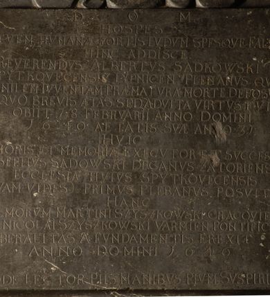 Zdjęcie nr 5: Tablica epitafijna w kształcie zbliżonym do kwadratu ujęta uszakami przechodzącymi w spływy wolutowe. Nad tablicą kartusz z godłem herbu Tępa Podkowa (wg Chrząńskiego odmiana typu c) i syglami A[LBERTUS] S[ADKOWSKI] P[LEBANUS] S[PYTKOVECENSIS] L[YPNICENSIS], zwieńczony krzyżem. Pod tablicą tarcza herbowa z godłem herbu Gozdawa i syglami I[OSEPHUS] S[ADKOWSKI] D[ECANVS] Z[ATORIENSIS] P[LEBANUS] S[PYTKOVeCENSIS]. Na tablicy inskrypcja: &quot;D[EO] O[PTIMO] M[AXIMO] / HOSPES / LEVEM HVMANAE FORTIS LVDVM SPESQVE FALSAS / HINC ADDISCE. / REVERENDVS ALBERTUS SADKOWSKI / SPYTKOVECENSIS LYPNICEN(IS) PLEBANVS QVI / SENILEM IVVENTAM PRAEMATVRA MORTE DEPOSVIT / IN QVO BREVIS AETAS SED ADVLTA VIRTVS FVIT / OBIIT 28 FEBRVARII ANNO DOMINI / 1640 AETATIS SVA ANNO 31 / HVIC / AMORIS ET MEMORIAE EXECVTOR ET SVCCESSOR / JOSEPHVS SADOWSKI DECANVS ZATORIENSIS / ECCLESIAE HVIVS SPYTKOVECENSIS / QVAM VIDES PRIMVS PLEBANVS POSVIT / HANC / ILL(USTRISI)MORUM MARTINI SZYSZKOWSKI CRACOVIEN[SIS] ET NICOLAI SZYSZKOWSKI VARMIEN[SIS] PONTIFICVM / LIBERALITAS A FVNDAMENTIS EREXIT / ANNO DOMINI 1646 / ADDE LECTOR PIIS MANIBVS PIVM SVSPIRIVM&quot;.

