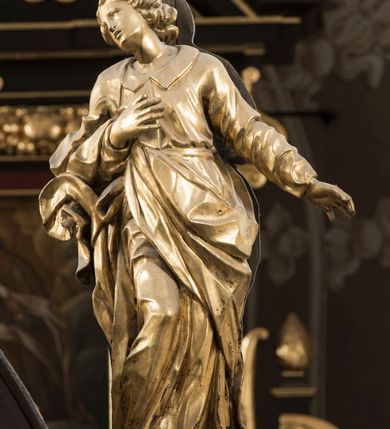 Zdjęcie nr 4: Na belce tęczowej o zarysie łuku wklęsło-wypukłego z uskokiem usytuowano krzyż z figurą Chrystusa i figury Marii i św. Jana Ewangelisty. Chrystus został przedstawiony frontalnie, w lekkim zwisie, z głową na wysokości dłoni, z nogami lekko ugiętymi w kolanach, skrzyżowanymi stopami, prawa na lewej, przybitymi do krzyża jednym gwoździem. Ręce rozłożone szeroko na ramionach krzyża, dłonie z lekko zgiętymi palcami są przebite gwoździami. Sylwetka Chrystusa jest delikatnie wygięta, głowa bezwładnie opada na prawe ramię. Jego twarz jest pociągła, nos prosty, wąski, oczy małe, zamknięte. Twarz okala szpiczasta, brązowa, krótka broda. Głowę przykrywają gęste, ciemne włosy o falistych, długich puklach zakrywające ucho i opadające na szyję oraz złota korona cierniowa. Ciało opracowane poprawnie pod względem anatomii, ale modelowane delikatnie, z lekko zarysowaną muskulaturą. Na biodrach krótkie perizonium, ze swobodnie opadającym wzdłuż prawego uda końcem materiału. W prawym boku Chrystusa widoczna jest rana od włóczni, z której wypływa krew, podobnie, jak z ran powstałych przez koronę cierniową, czy w miejscach przebitych gwoździami. Belka łuku tęczowego w kolorze brązowym, z fragmentami profilowania złoconymi. Rzeźba Chrystusa polichromowana naturalistycznie, ze złoconym perizonium oraz koroną cierniową i czerwonymi strużkami krwi.