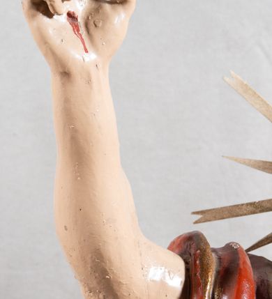 Zdjęcie nr 6: Rzeźba całopostaciowa, pełnoplastyczna, ustawiona na cokole w formie obłoku. Sylwetka Jezusa zwrócona na wprost, w wydatnym kontrapoście, z prawą nogą wspartą na leżącej na podstawie czaszce. Głowa Jezusa uniesiona, skierowana delikatnie w prawo. Twarz pociągła, o kwadratowym zarysie szczęki, o głęboko osadzonych oczach z drążonymi kącikami, zwróconych ku górze; prostym, długim nosie, rozchylonych ustach; okolona krótką kręconą brodą, układającą się w dwa pukle. Włosy długie, gęste, kręcone, układające się w wijące pasma, opadające na ramiona. Jezus w lewej ręce trzyma czerwony sztandar na drzewcu zakończonym krzyżem, prawą unosi wysoko w geście błogosławieństwa. Ciało o delikatnie zarysowanej muskulaturze z zaznaczonymi śladami męki. W partii bioder przepasany złoconym perizonium przewiązanym sznurem, sięgającym połowy uda i odsłaniającym lewe biodro; tkanina drapowana w grube fałdy, marszczona, z wywiniętym brzegiem. Na ramiona narzucony czerwony płaszcz opadający na plecy, drapowany w proste fałdy, z zawiniętym brzegiem. Głowę ujmuje gloria promienista.