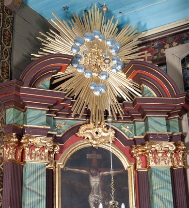 Zdjęcie nr 2: Ołtarz przyścienny, architektoniczny, z mensą w formie sarkofagu, dwustrefową, o wklęsło-wypukłych bokach. Mensa z kamiennym portatylem. Retabulum jednoosiowe, jednokondygnacyjne, ustawione na wysokim cokole, ujęte parą półfilarów kompozytowych o kanelowanych trzonach ustawionych na tle podwójnych pilastrów, z których zewnętrzne dostawione ukośnie. Podpory wspierają wyłamujące się belkowanie z architrawem wygiętym w  łuk nadwieszony nad polem środkowym i wydatnym, profilowanym gzymsem.  W zwieńczeniu przerwany, półkolisty przyczółek oraz gloria promienista z obłokami, pośrodku których aplikowany hierogram IHS. 
W polu środkowym wycięta wnęka ujęta profilowaną ramą, w kształcie stojącego prostokąta, zamkniętego łukiem nadwieszonym. We wnęce obraz z przedstawieniem  Ukrzyżowania Chrystusa, nad którym rzeźbiony kartusz formowany z ornamentu rocaille'owego.
Całość struktury ołtarza malowana w kolorze ciemnobrązowym, Półfilary, fryz oraz mensa pokryte malowaną marmoryzacją w odcieniach zieleni, pole środkowe ciemnoczerwone, detal architektoniczny  i profilowania pozłacane.